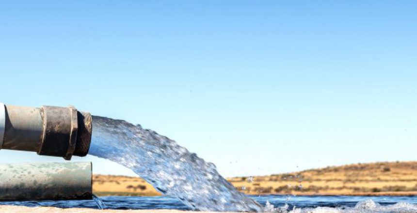 A Large stream of water gushing out of a pipe and filling a ceme